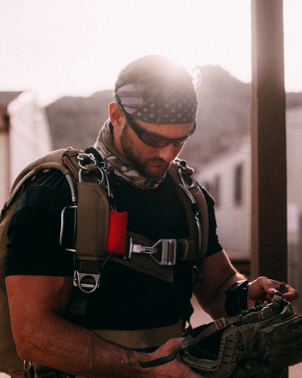 Alexander rigging up at golden hour, freefall harness and stars-and-stripes shemagh